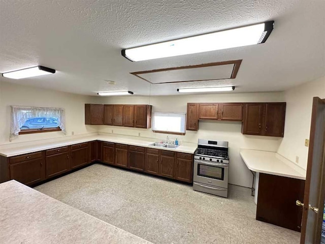 kitchen with a textured ceiling, sink, and stainless steel gas range