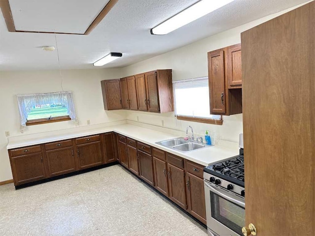 kitchen featuring sink, a textured ceiling, and stainless steel gas range