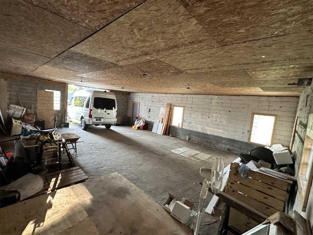 misc room featuring plenty of natural light, brick wall, and vaulted ceiling