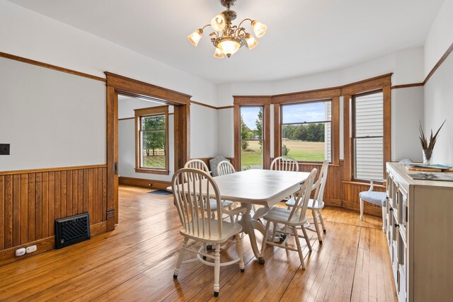 5721 Broomhead Rd, Williamsburg, MI 49690 - dining room featuring a chandelier, a wainscoted wall, light wood finished floors, and wood walls