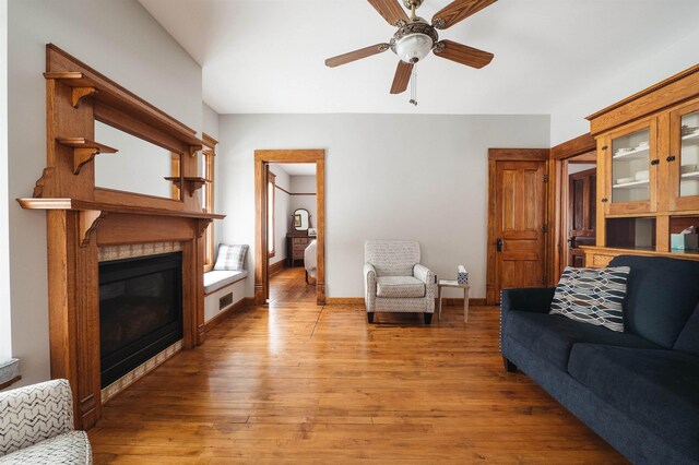 5721 Broomhead Rd, Williamsburg, MI 49690 - living room featuring light wood finished floors, ceiling fan, a glass covered fireplace, and baseboards