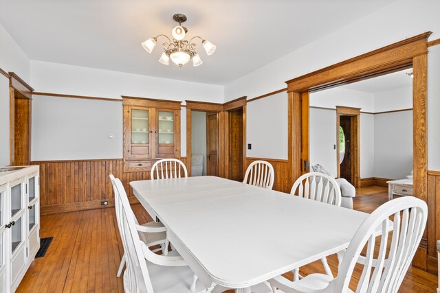 5721 Broomhead Rd, Williamsburg, MI 49690 - dining room with a wainscoted wall, a chandelier, light wood-style flooring, and wood walls