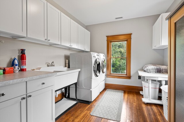 5721 Broomhead Rd, Williamsburg, MI 49690 - laundry area with cabinet space, independent washer and dryer, dark wood finished floors, and baseboards