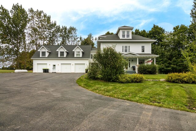 5721 Broomhead Rd, Williamsburg, MI 49690 - view of front of house featuring a garage, a front lawn, driveway, and covered porch