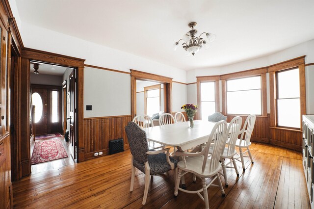 5721 Broomhead Rd, Williamsburg, MI 49690 - dining room featuring wainscoting, a chandelier, light wood finished floors, and wood walls