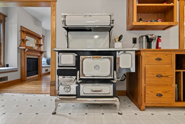 5721 Broomhead Rd, Williamsburg, MI 49690 - kitchen featuring a fireplace, open shelves, and brown cabinets