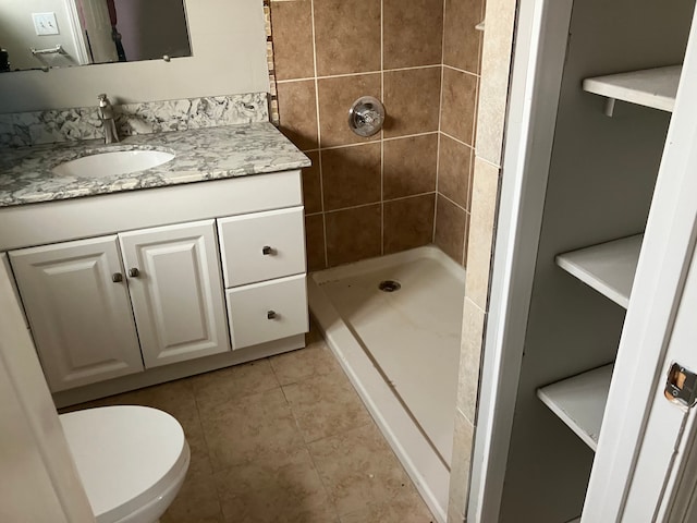 bathroom featuring tiled shower, vanity, toilet, and tile patterned flooring