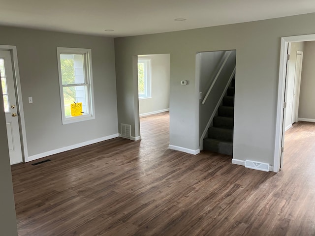 unfurnished living room featuring dark hardwood / wood-style flooring and plenty of natural light