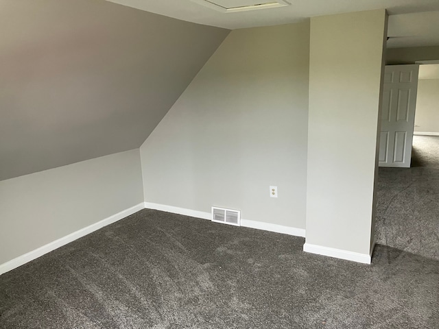 additional living space featuring vaulted ceiling and dark colored carpet