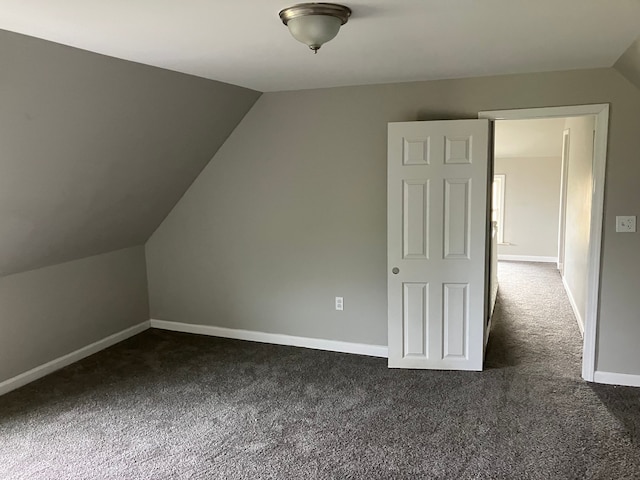 bonus room with dark carpet and vaulted ceiling