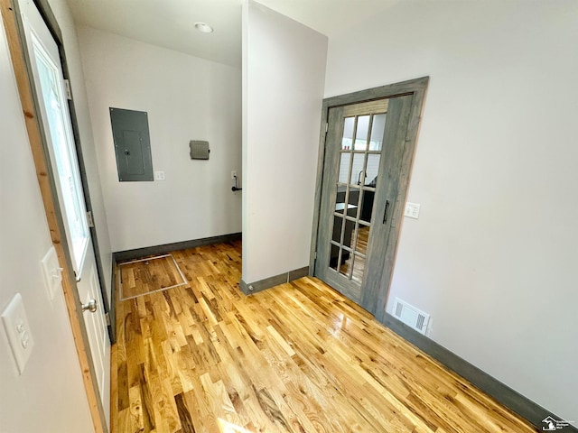 corridor with electric panel and light hardwood / wood-style flooring