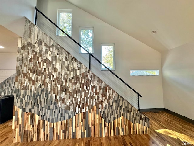 stairs featuring plenty of natural light, lofted ceiling, and hardwood / wood-style flooring