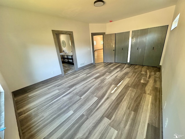 unfurnished bedroom featuring hardwood / wood-style floors and two closets