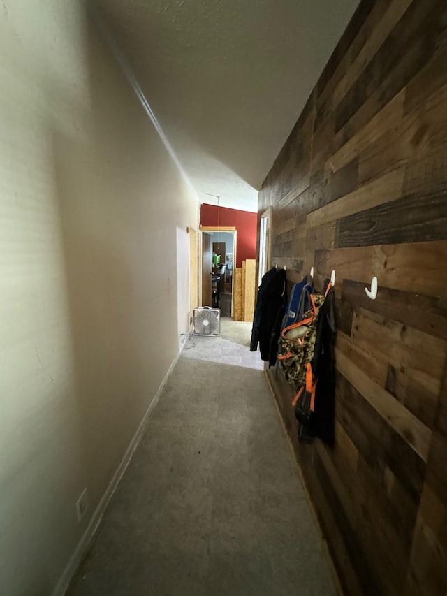 hall featuring vaulted ceiling and wood walls