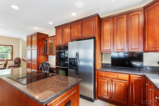 kitchen with light tile patterned flooring, a kitchen island, dark stone countertops, and black appliances