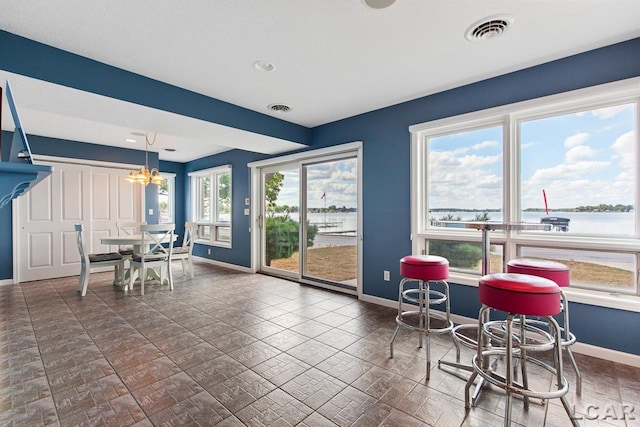 dining area with a chandelier, a water view, and plenty of natural light