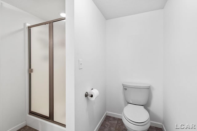 bathroom featuring toilet and a shower with door