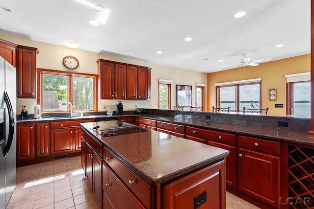 kitchen with kitchen peninsula, a textured ceiling, a wealth of natural light, and black cooktop