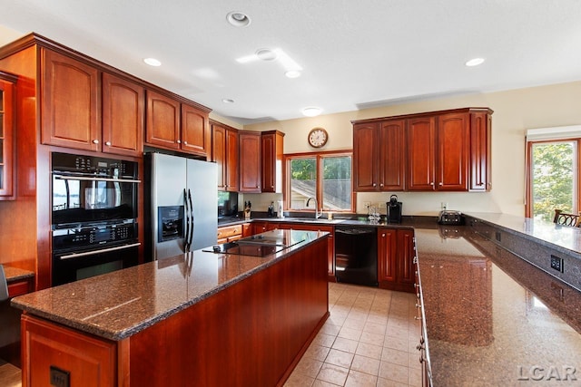 kitchen with dark stone countertops, a healthy amount of sunlight, sink, and black appliances