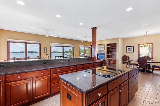 kitchen featuring hanging light fixtures, a kitchen island, dark stone countertops, black electric stovetop, and a water view