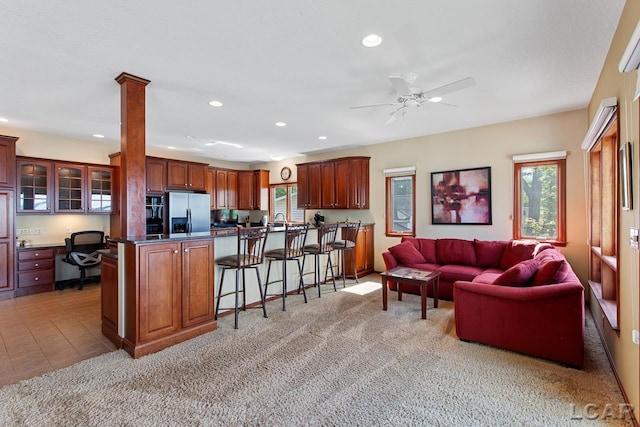 living room with ceiling fan, ornate columns, sink, and light tile patterned floors