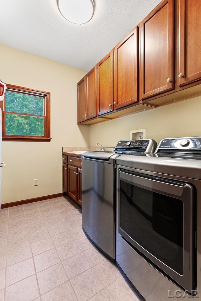 laundry room featuring cabinets, light tile patterned floors, and washer and dryer