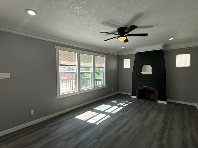 unfurnished living room featuring ceiling fan, dark wood-type flooring, crown molding, a textured ceiling, and a fireplace