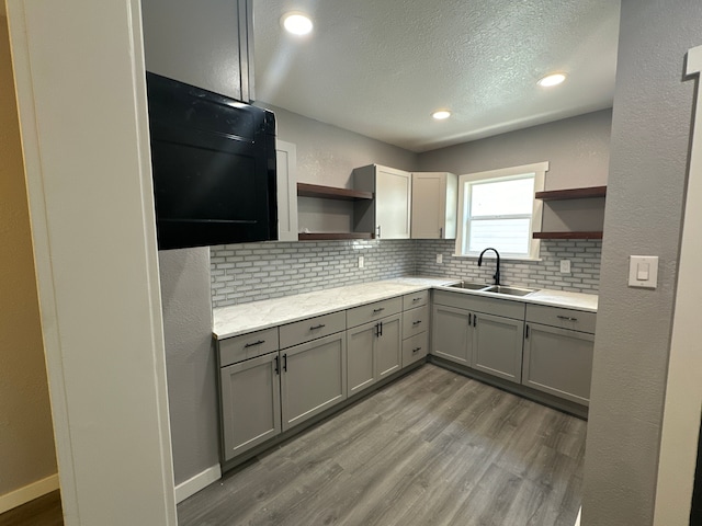 kitchen with decorative backsplash, gray cabinetry, a textured ceiling, sink, and light hardwood / wood-style flooring