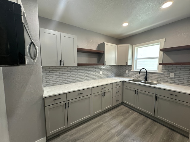 kitchen with decorative backsplash, gray cabinets, light hardwood / wood-style flooring, and sink