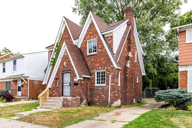 16184 Manor St, Detroit, MI 48221 - tudor house with a shingled roof, brick siding, a chimney, and a gate