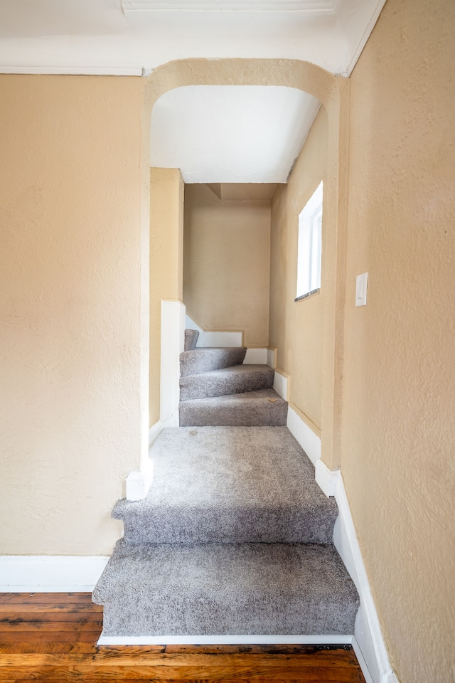 16184 Manor St, Detroit, MI 48221 - staircase featuring baseboards, a textured wall, arched walkways, and wood finished floors