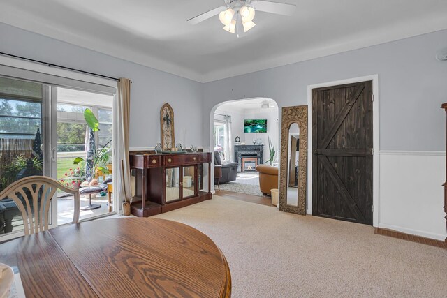10526 Spring Arbor Rd, Spring Arbor, MI 49283 - carpeted dining space with a ceiling fan, arched walkways, and a glass covered fireplace