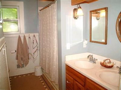 5295 Belding Rd NE, Rockford, MI 49341 - full bath with double vanity, curtained shower, and a wainscoted wall