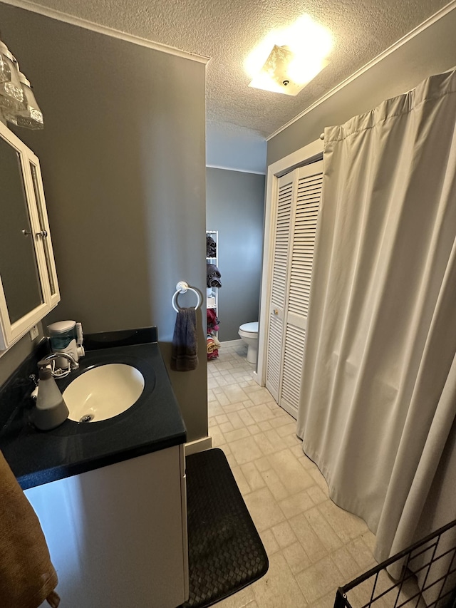 bathroom with a textured ceiling, vanity, and toilet