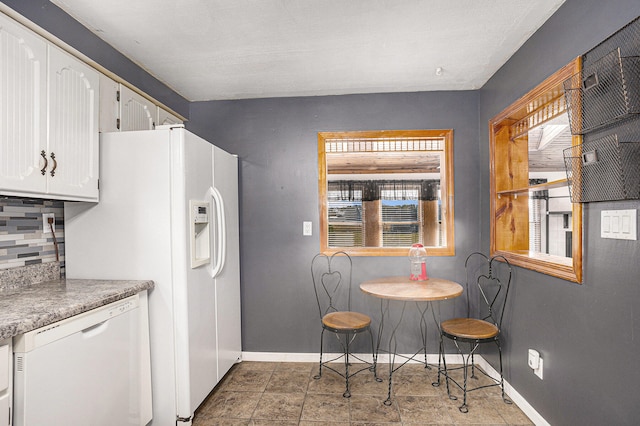 kitchen featuring white cabinets, decorative backsplash, and white appliances