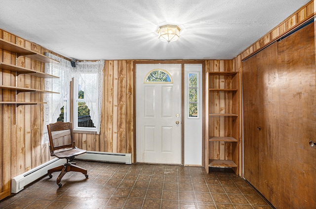 foyer entrance with a textured ceiling, a baseboard radiator, and wood walls