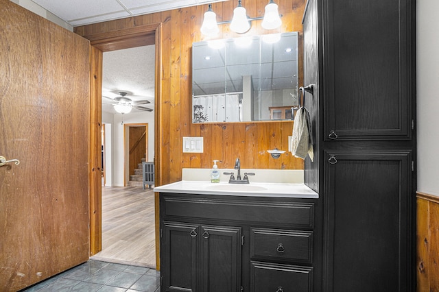 bathroom with a shower with shower curtain, vanity, ceiling fan, hardwood / wood-style floors, and wood walls