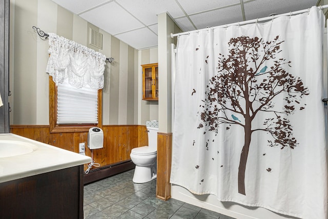 full bathroom with a paneled ceiling, a baseboard heating unit, tile patterned floors, wooden walls, and shower / bathtub combination with curtain