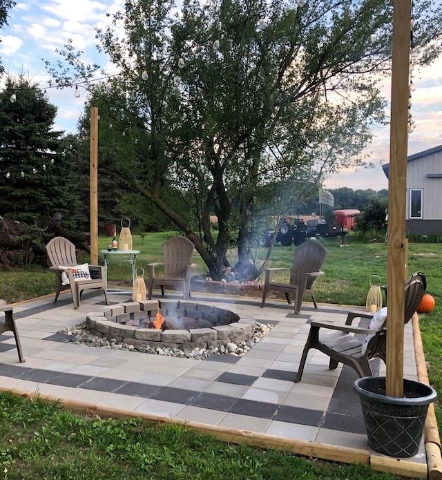 patio terrace at dusk featuring a yard and an outdoor fire pit