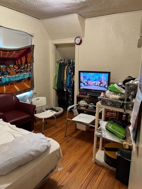 bedroom featuring a textured ceiling, hardwood / wood-style flooring, a closet, and lofted ceiling