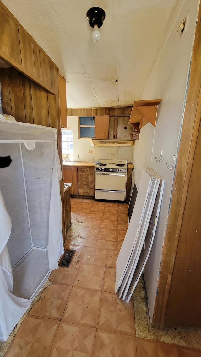 3376 Swihart Rd, Brethren, MI 49619 - kitchen with white gas range oven, brown cabinetry, and light floors