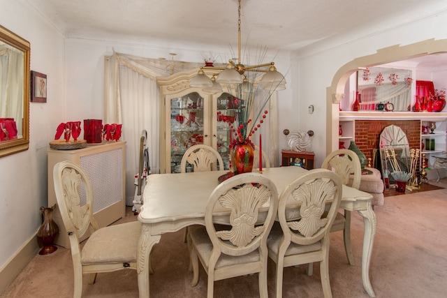 carpeted dining area featuring a fireplace, ornamental molding, and a notable chandelier