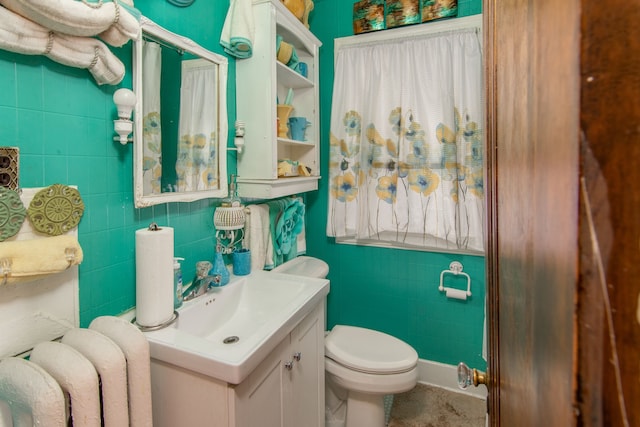 bathroom featuring radiator heating unit, vanity, tile walls, and toilet