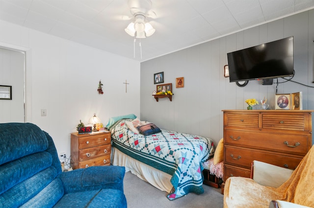 bedroom featuring ceiling fan, carpet, and wood walls