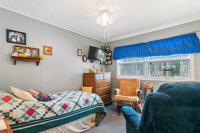 carpeted bedroom featuring ceiling fan and wooden walls