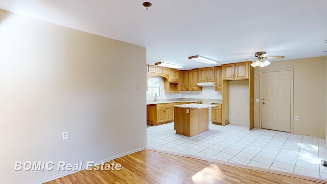 kitchen featuring light hardwood / wood-style floors, a kitchen island, ceiling fan, and sink