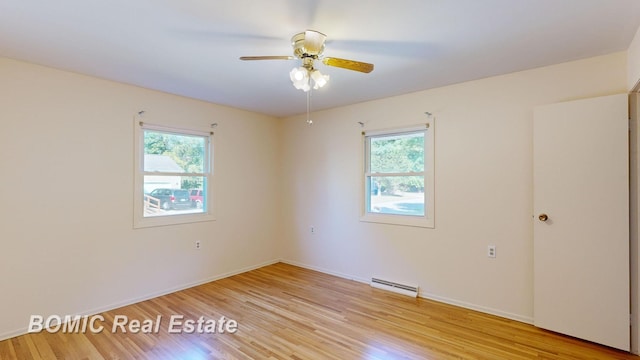 empty room featuring a wealth of natural light, ceiling fan, light hardwood / wood-style floors, and a baseboard heating unit