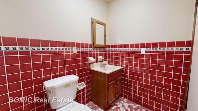 bathroom with vanity, tile walls, and toilet