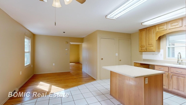 kitchen with light wood-type flooring, a center island, a wealth of natural light, and ceiling fan