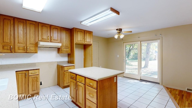 kitchen with tasteful backsplash, ceiling fan, a center island, and light tile patterned floors